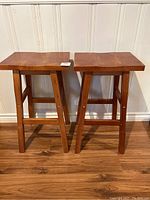 Front view of two wooden bar stools showing rectangular seats and legs