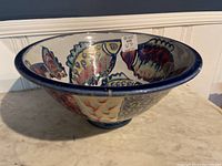 Side view of large ceramic bowl with colorful fish patterns and 16" diameter size label