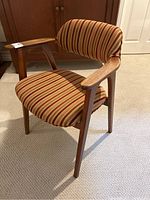 Front-side angle showing teak wood frame, armrests, and fabric upholstery with striped pattern on seat and backrest.