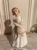 Front view of Royal Doulton porcelain figurine showing a girl holding a cat.