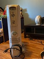 Full front view of Noma space heater showing power cord wrapped at base and heater body.