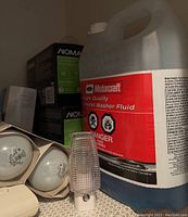 Large jug of Motorcraft windshield washer fluid next to boxed light bulbs and a small plug-in device