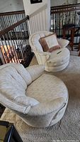 Two round swivel chairs with diamond patterned light beige upholstery and one beige/brown pillow, showing wear and pet damage.
