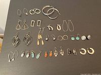 20 pairs sterling silver earrings arranged on black background