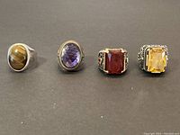 Front view of four rings side by side showing shape and color of stones