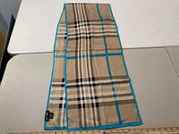 Beige and turquoise check silk scarf laid flat with ruler for scale