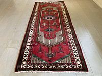 Full length view of red field runner with ivory border on wood floor