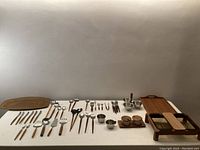 Wide view of collection laid out on table showing utensils, trays, and condiment sets