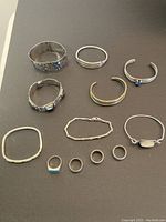 Overview of all 8 bracelets arranged above 4 rings on black background