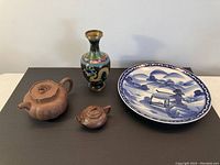 Overview of two Yixing clay teapots, cloisonné vase and blue & white charger on table