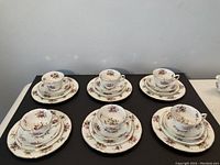 Overall view of six place settings each with tea cup, saucer, side plate, and dessert plate, porcelain tea set arranged in good condition