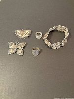 Full lot overview showing all five silver filigree jewelry pieces on dark background.