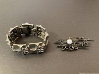 Overview of bracelet and brooch on black background