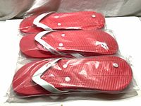 Three pairs of red flip flop beach sandals sealed in plastic bags, stacked on each other showing size and condition.