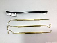 Full view of all 4 pieces: one black nylon brush with white bristles, three brass picks with different shaped tips and knurled handles.
