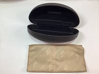 Open dark brown Serengeti hard sunglass case with Serengeti branded velvet lens cleaning cloth spread in front.