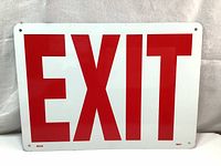 Front view of aluminum EXIT sign with large red letters on white background and pre-drilled mounting holes