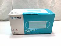 Box of 50 blue ASTM Level 2 face masks by Pri-Med Medical Products, showing branding and mask illustration on front.