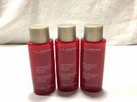 Three red bottles of Clarins Multi-Intensive Super Restorative Treatment Essence arranged side by side with front labels visible.