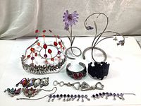 Full lot with all jewelry parts, bracelets, tiara, and decorative stands arranged on white surface with grey curtain backdrop