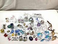 Wide view of the collection showing various Swarovski crystal parts, mostly small figurines and loose crystals in multiple colors arranged on white background.