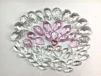Top-down image of clear and pink tear drop Swarovski crystals arranged in semi-circle and cluster, showing size and color variations.