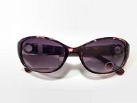 Front view of the sunglasses showing large oval-shaped purple gradient lenses with UV protection sticker on the right lens.