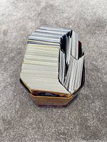 Stack of Pokémon cards inside a tin showing the thick collection including holo and reverse holo cards.