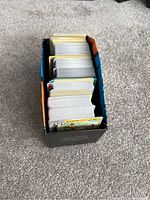 View from top showing a black Pokemon Elite Trainer Box filled with multiple stacks of Pokemon trading cards.