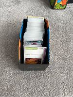 Open Pokémon Elite Trainer Box showing a large stack of assorted Pokémon cards inside.