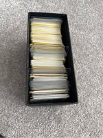 Top-down view of a black Elite Trainer Box filled with many sleeved yellow-backed Pokémon trading cards.