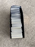 Stack of Pokémon cards inside a black Pokémon Elite Trainer Box shown from above.