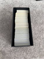 Top-down view showing a black Pokémon Elite Trainer Box filled with a large stack of Pokémon cards neatly organized inside.