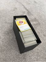 Black Pokémon Elite Trainer Box loaded with assorted Pokémon cards stacked inside.
