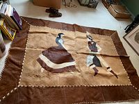 Full view of rectangular cowhide area rug laid flat showing central dancers scene and stitched border