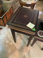 First photo showing the larger book design end table with a closed lid, decorative gold borders, and center motif.