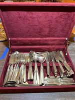 Full view of velvet-lined box holding the flatware set with forks, spoons, and knives