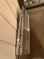 Folded aluminum ramp lying on carpeted floor, showing hinge and locking clasp details.
