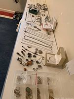 Overview of lot on white table including various silver necklaces, bracelets, rings, earrings, charms and boxes
