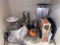 Wide view of the small kitchen appliances including blender, food processor, donut machine in original box, and warming plate.