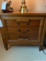 Front view of one Thomasville wooden nightstand showing two-drawer design and brass-tone hardware
