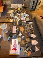 Overhead view of the assorted vintage collectibles and novelties on table including figurines, maracas, diecast cars, calendar, and three Stooges faces.