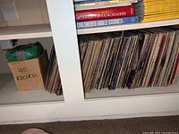 White built-in shelf with rows of LP albums and a cardboard box labeled ‘45 records’
