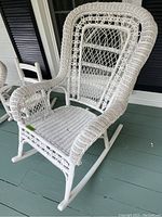 Full view of the white wicker rocking chair showing the full seat, armrests, and rockers on the floor.