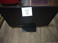 Front view of the 23-inch Samsung flat screen TV showing the screen and base with a tag on the screen.