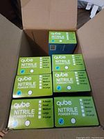 Seven unopened boxes of Qube nitrile gloves in green boxes, all size small, powder free.
