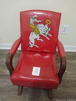 Front view of antique child's rocking chair with red vinyl upholstery and cowboy on horse graphic on the backrest