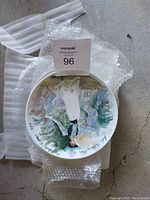 Top view of one collector plate showing hand-painted scene of a woman in historical dress with floral background.