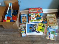 Overview of the lot showing the box of track pieces, shape sorting box, houseboat toy, and assortment of books and cards