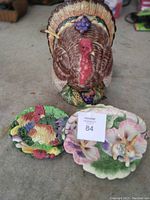 Large ceramic turkey tureen with two ceramic dishes in front, including a rooster platter and a floral Easter basket dish with bunny.